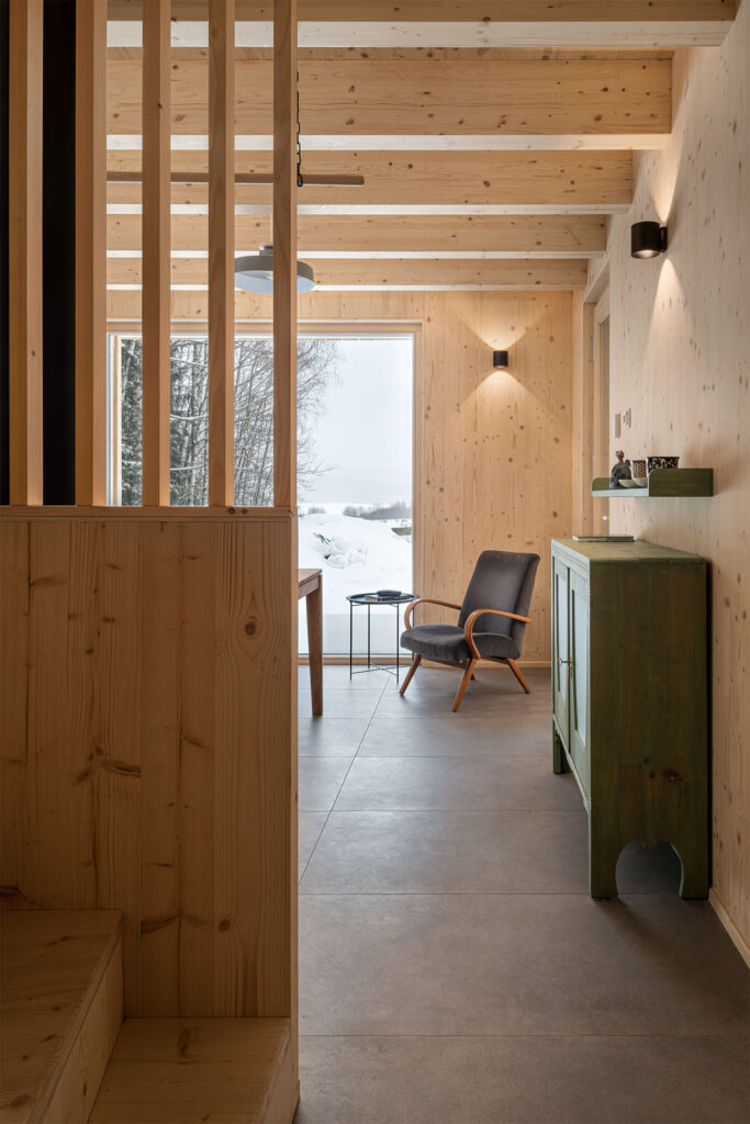 Dřevěný interiér s výhledem na sníh a přírodní křeslo