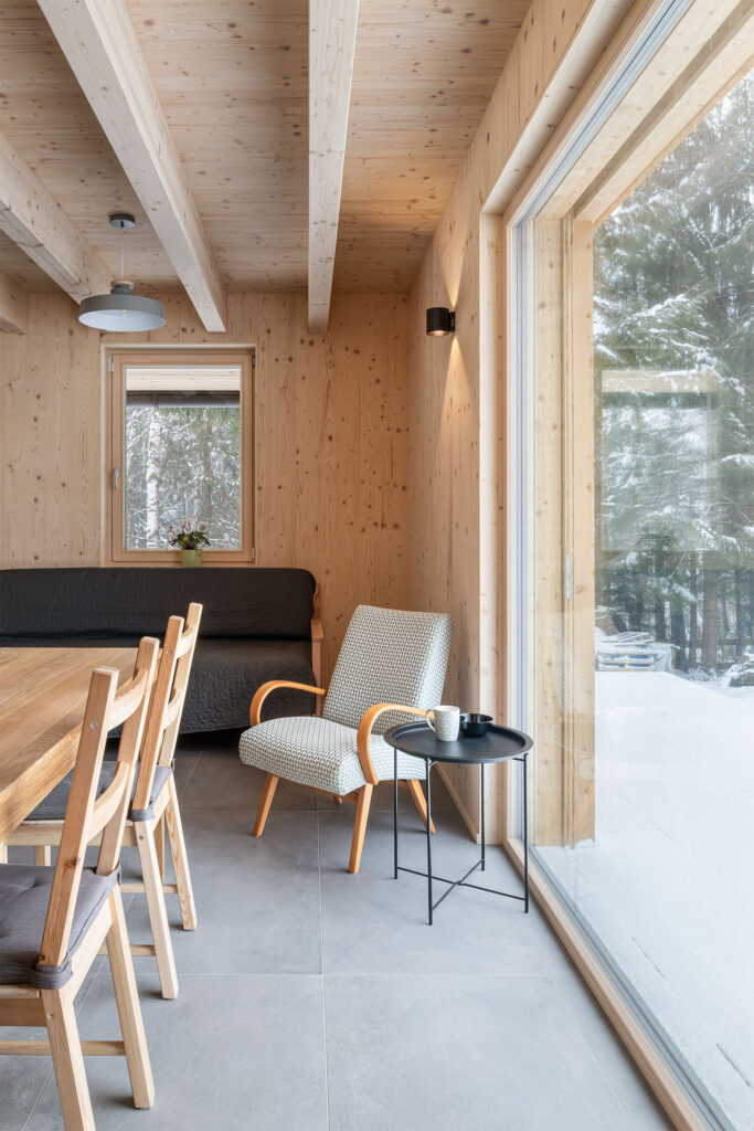 Křeslo u velkého okna s výhledem na les v dřevostavbě